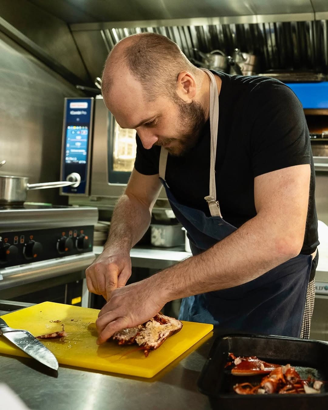 A chef preparing lobster in the Saltline & Ember kitchen.