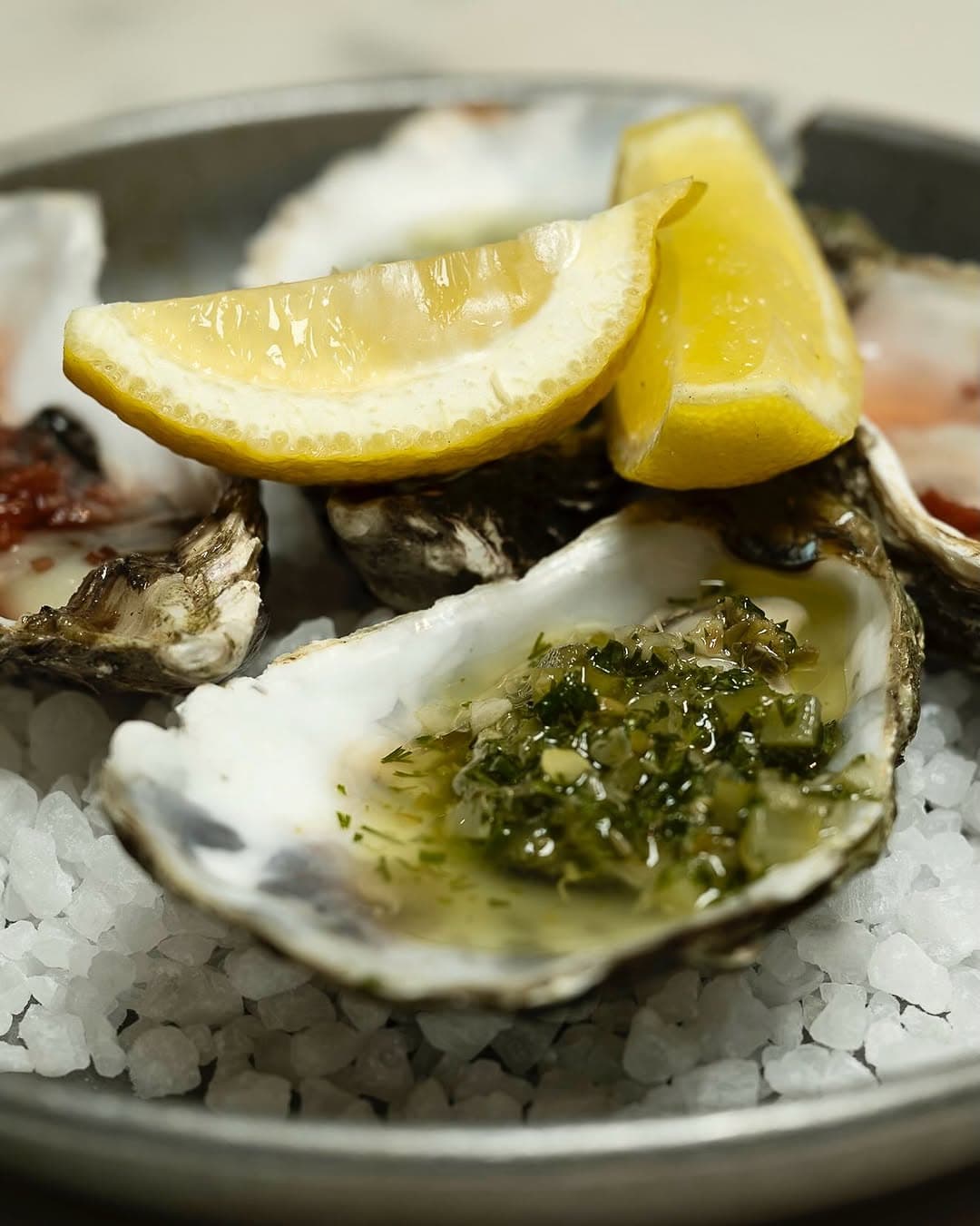 A dressed oyster with lemon on a bed of salt.